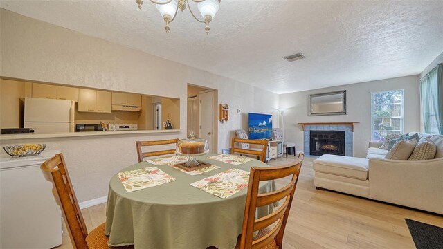 3609 59th Ave W Unit 4045, Bradenton, FL 34210 - dining room with a textured ceiling, light wood-type flooring, a fireplace, and a chandelier