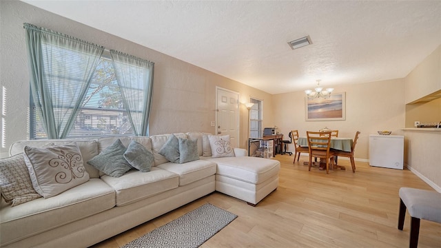 living room featuring light hardwood / wood-style floors, a textured ceiling, and an inviting chandelier