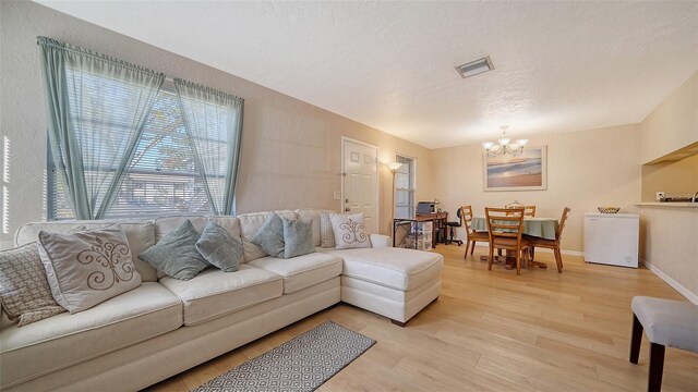 3609 59th Ave W Unit 4045, Bradenton, FL 34210 - living room featuring a chandelier, light wood-style flooring, a textured ceiling, and baseboards