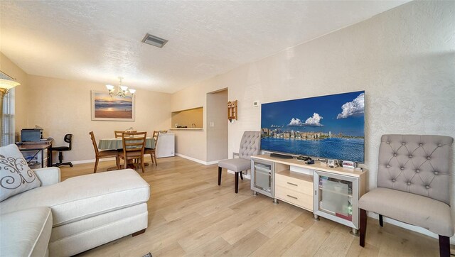 3609 59th Ave W Unit 4045, Bradenton, FL 34210 - living area with light wood-type flooring, a chandelier, a textured ceiling, and baseboards