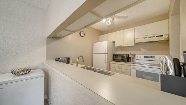 3609 59th Ave W Unit 4045, Bradenton, FL 34210 - kitchen with under cabinet range hood, white appliances, a textured wall, a sink, and light countertops