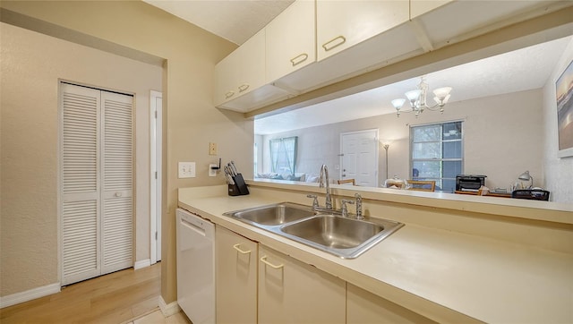 kitchen with a healthy amount of sunlight, sink, white dishwasher, and hanging light fixtures