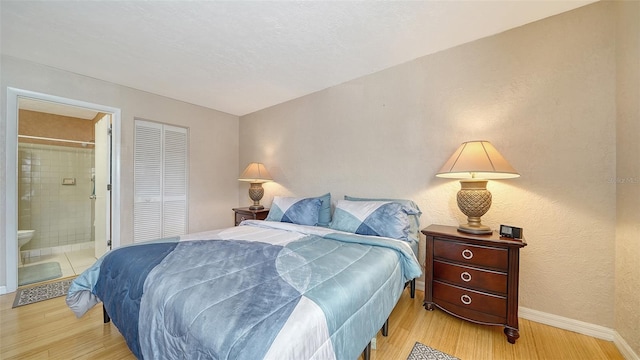 bedroom featuring ensuite bath, a closet, and light hardwood / wood-style flooring