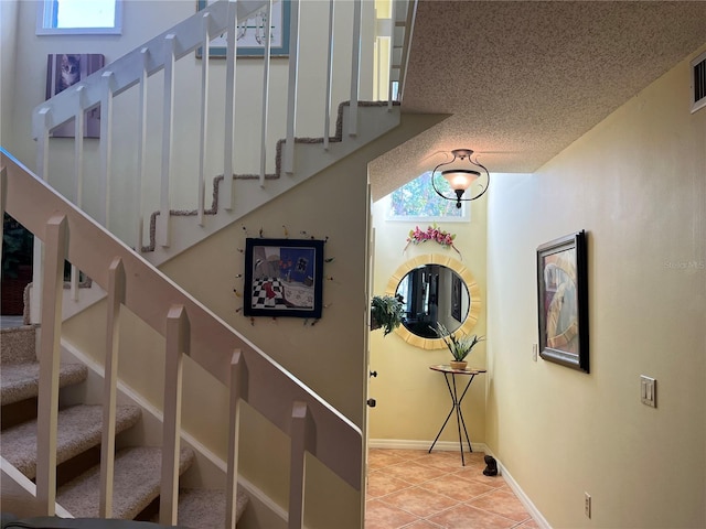 stairs with tile patterned floors and a textured ceiling