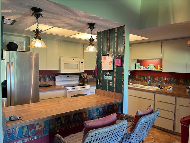 kitchen with pendant lighting, white appliances, sink, and wooden counters