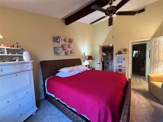 bedroom with carpet, ceiling fan, a spacious closet, beamed ceiling, and a closet