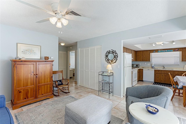 tiled living room featuring ceiling fan, sink, and a textured ceiling