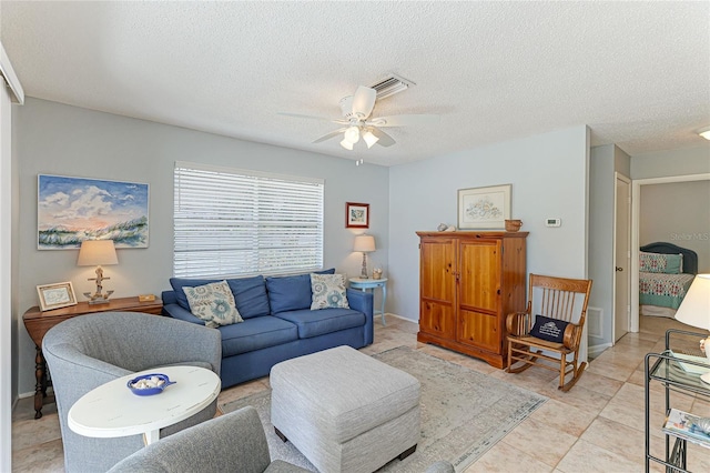 living room featuring ceiling fan and a textured ceiling