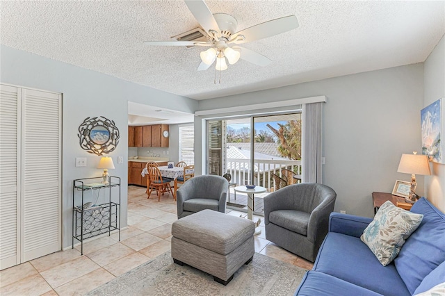 living room with a textured ceiling, ceiling fan, and light tile patterned flooring