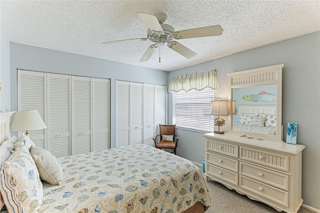 carpeted bedroom featuring a textured ceiling, ceiling fan, and multiple closets