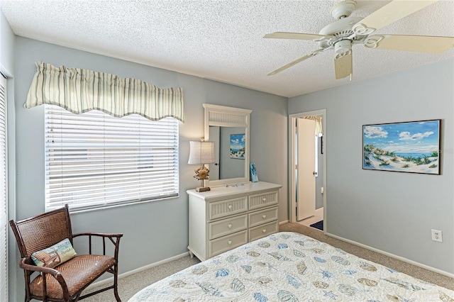 bedroom featuring a textured ceiling, light colored carpet, and ceiling fan