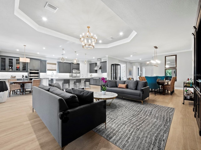 living room with plenty of natural light, crown molding, a chandelier, and light hardwood / wood-style flooring