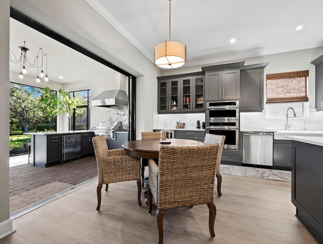 dining space featuring light wood-type flooring, ornamental molding, and sink