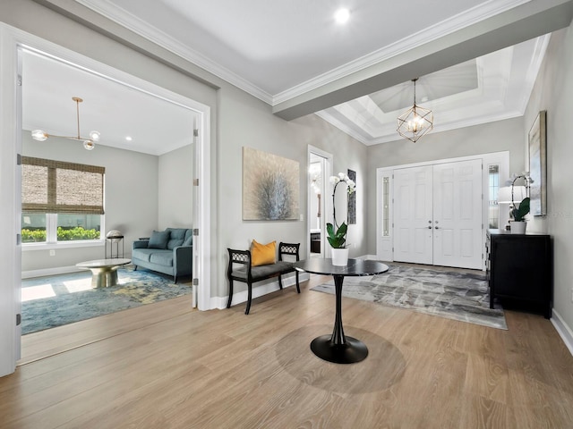 foyer entrance featuring a raised ceiling, an inviting chandelier, light hardwood / wood-style flooring, and crown molding