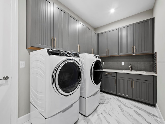 clothes washing area featuring washing machine and clothes dryer, sink, and cabinets