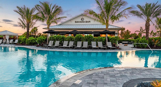 pool at dusk with a gazebo and a patio