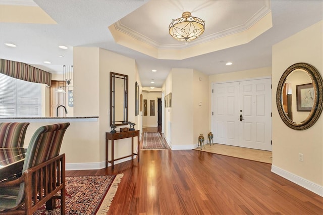 entryway featuring hardwood / wood-style floors, a raised ceiling, ornamental molding, and sink