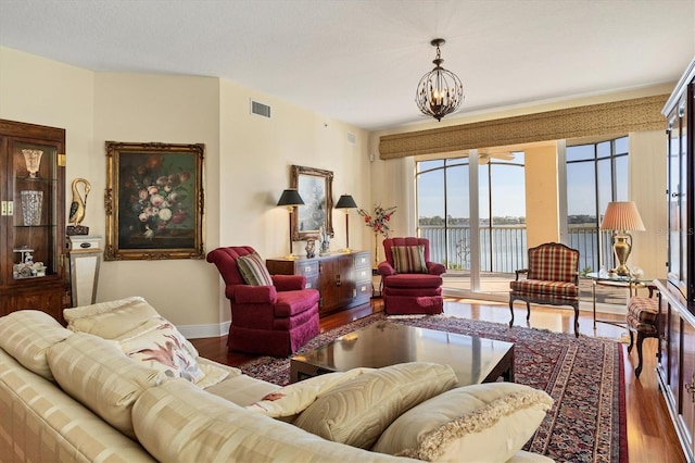 living room with a chandelier, dark hardwood / wood-style flooring, and a water view