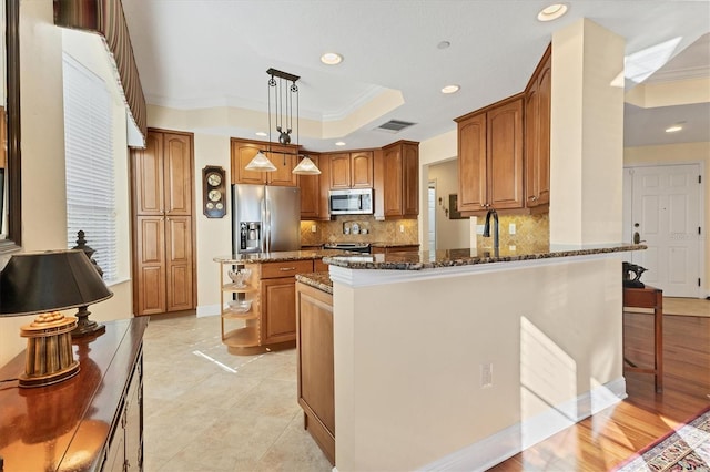 kitchen featuring decorative backsplash, appliances with stainless steel finishes, dark stone counters, crown molding, and pendant lighting