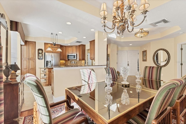 dining space featuring light wood-type flooring, a tray ceiling, an inviting chandelier, and ornamental molding