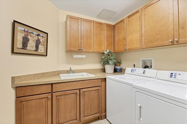 washroom featuring a textured ceiling, cabinets, sink, and washing machine and clothes dryer