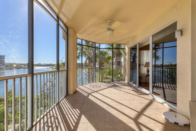 unfurnished sunroom with ceiling fan and a water view