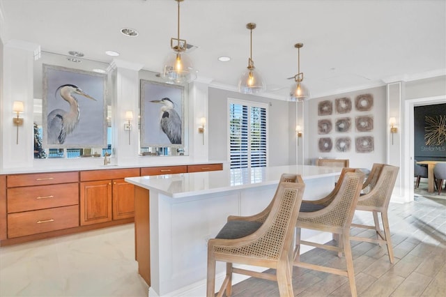 kitchen featuring sink, a center island, decorative light fixtures, a breakfast bar, and ornamental molding