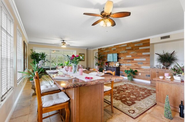 dining area with crown molding, ceiling fan, and wooden walls