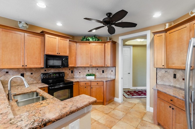 kitchen featuring light stone countertops, decorative backsplash, sink, and black appliances