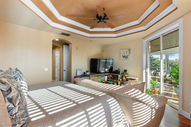 bedroom with hardwood / wood-style flooring, ceiling fan, crown molding, and a tray ceiling