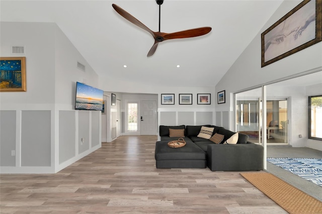 living room with light hardwood / wood-style floors, high vaulted ceiling, ceiling fan, and a healthy amount of sunlight