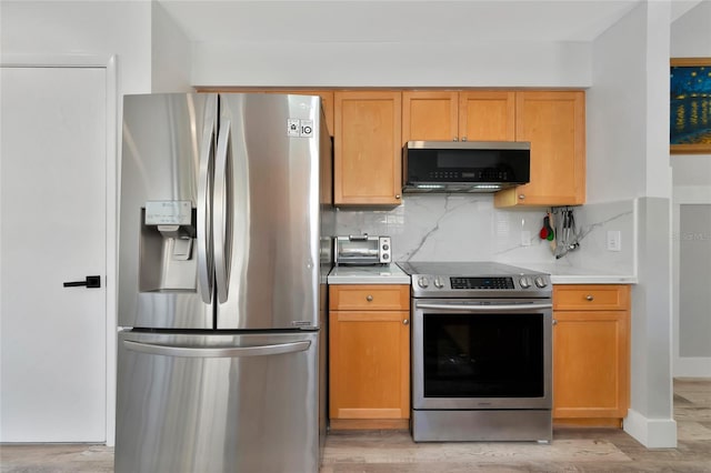 kitchen with light wood-type flooring, appliances with stainless steel finishes, and tasteful backsplash