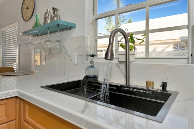 interior details featuring decorative backsplash, light stone countertops, and sink