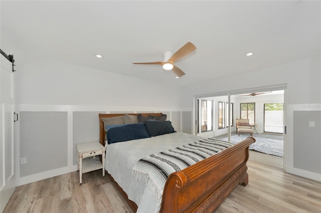 bedroom with a barn door, light hardwood / wood-style floors, and ceiling fan