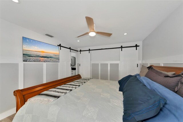 bedroom with a barn door and ceiling fan