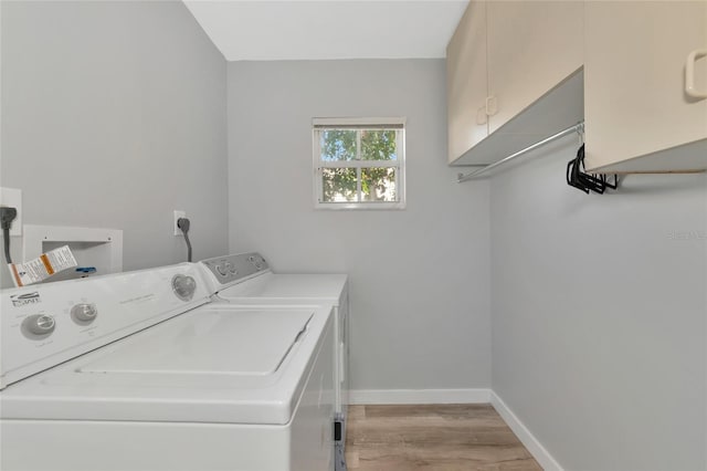 laundry area with washer and dryer, light hardwood / wood-style flooring, and cabinets