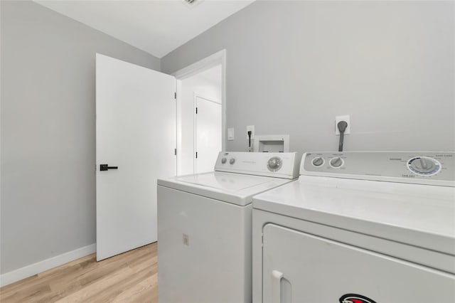 clothes washing area with independent washer and dryer and light hardwood / wood-style flooring