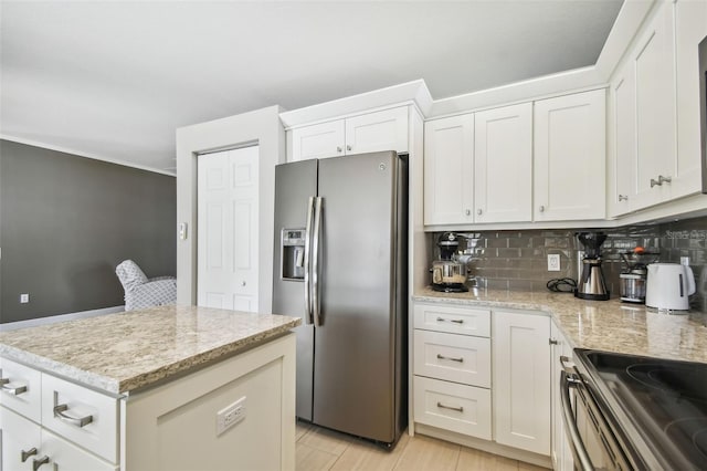 kitchen with white cabinets, light stone countertops, appliances with stainless steel finishes, tasteful backsplash, and light hardwood / wood-style floors