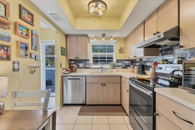 kitchen with sink, plenty of natural light, light brown cabinetry, light tile patterned floors, and appliances with stainless steel finishes