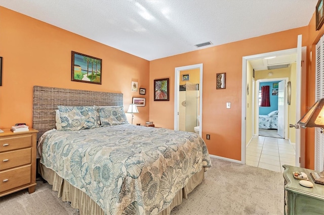 bedroom with a textured ceiling, connected bathroom, and light colored carpet