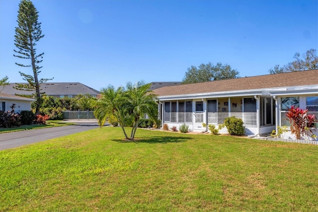 ranch-style home featuring a sunroom, aphalt driveway, and a front lawn