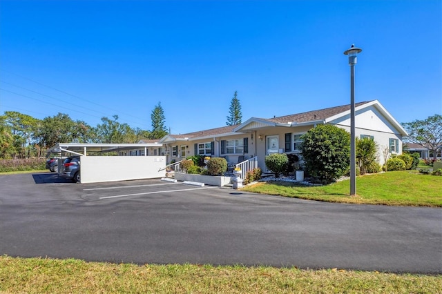 ranch-style house with covered and uncovered parking and a front lawn