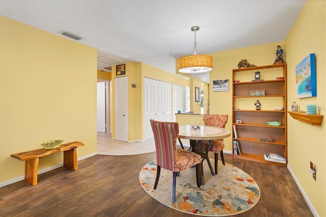 dining area with wood finished floors, visible vents, and baseboards