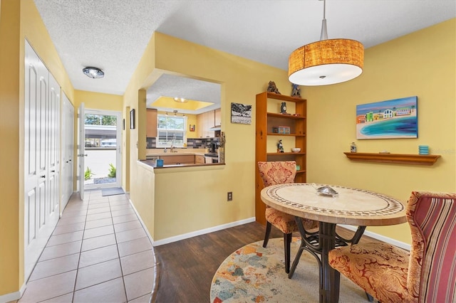 dining room with baseboards, a textured ceiling, and wood finished floors