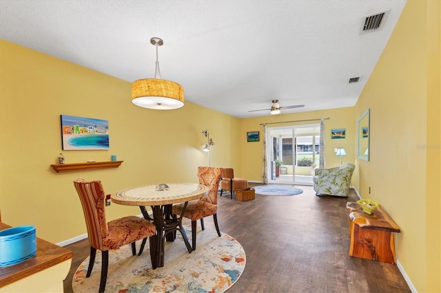 dining space with baseboards, visible vents, and dark wood finished floors