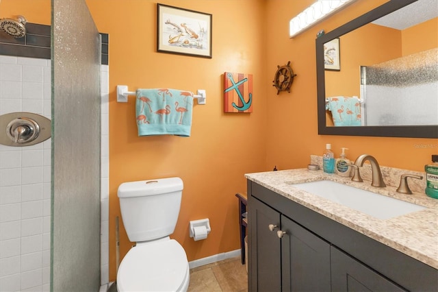 bathroom with tiled shower, vanity, toilet, and baseboards