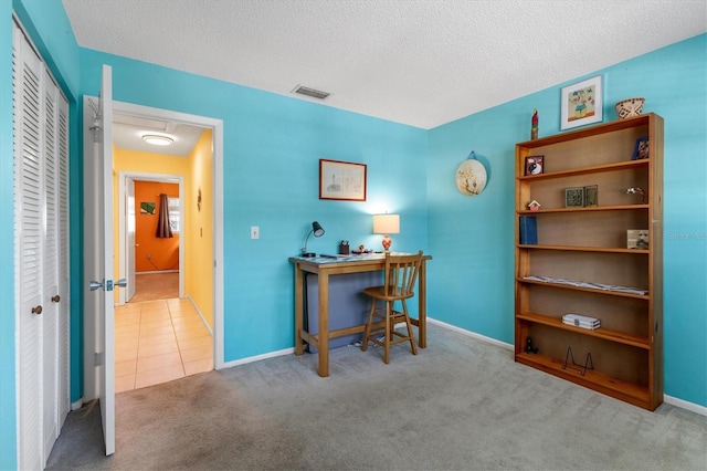 home office with a textured ceiling, tile patterned flooring, visible vents, baseboards, and carpet