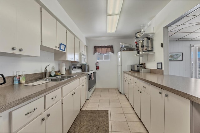 kitchen with light tile patterned floors, light countertops, white cabinetry, a sink, and white appliances