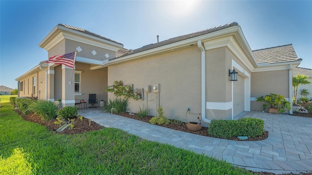 7525 Alumni Trl, Sarasota, FL 34243 - view of home's exterior featuring an attached garage, stucco siding, a lawn, and driveway