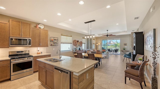 kitchen with hanging light fixtures, stainless steel appliances, a tray ceiling, and ceiling fan